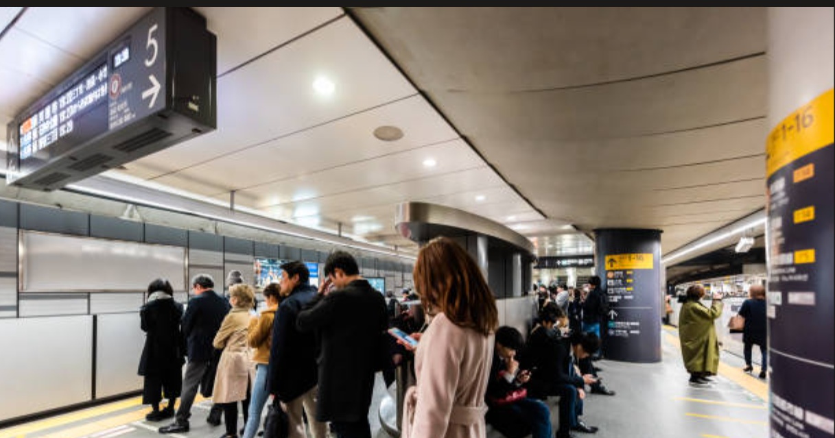 Persone in fila ordinata alla metro di Tokyo
